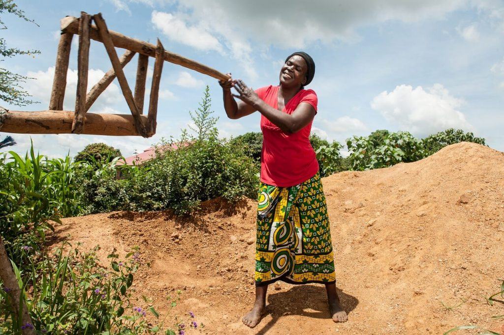 A smiling African woman holds onto a wooden fixture.